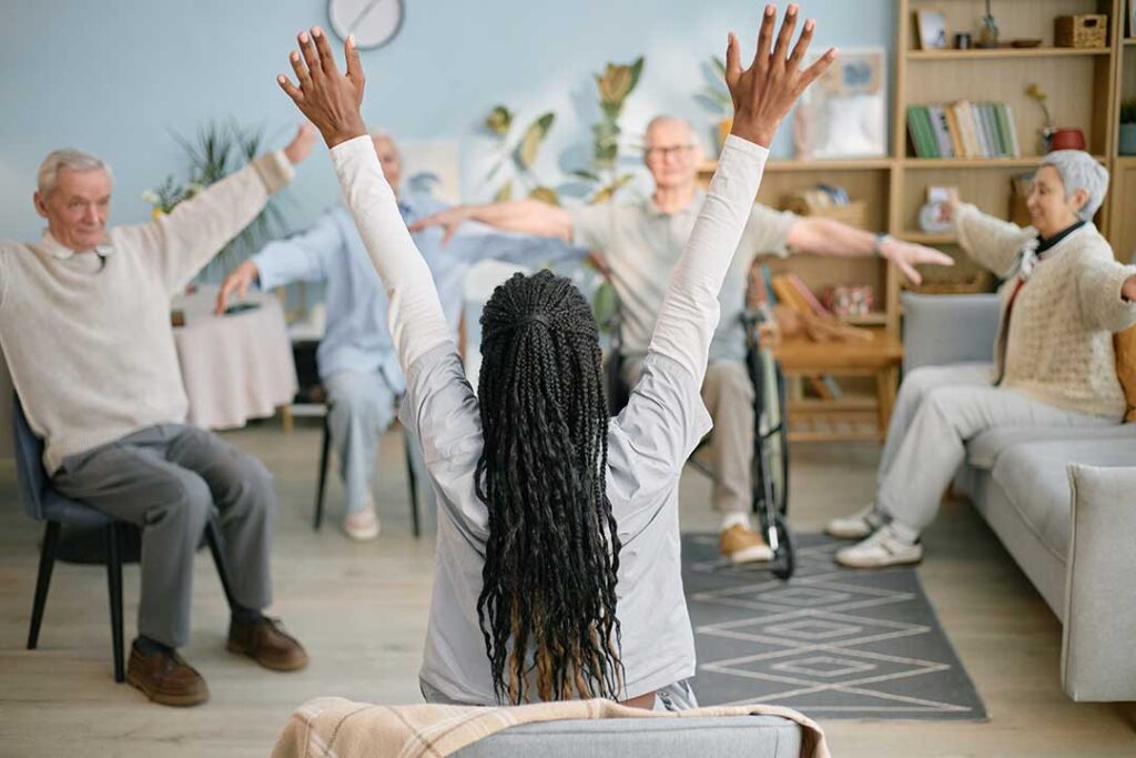 Older adults sharing conversation and a card game at a comfortable communal table.