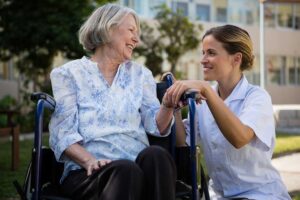 Older adult enjoying a balanced meal at a bright assisted living dining table with a caregiver nearby.